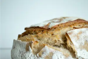 Close up of crusty homemade bread in front of a white background.