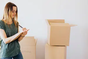 Woman taking notes about contents of her boxes for storage unit cleanout.