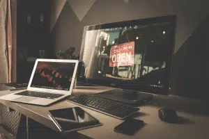 A laptop, tablet, phone and desktop computer sitting on a desk.