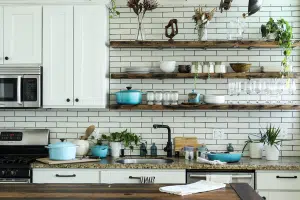 White kitchen with open shelving with plants, plates, and cups on it - a great way to get extra household storage space.