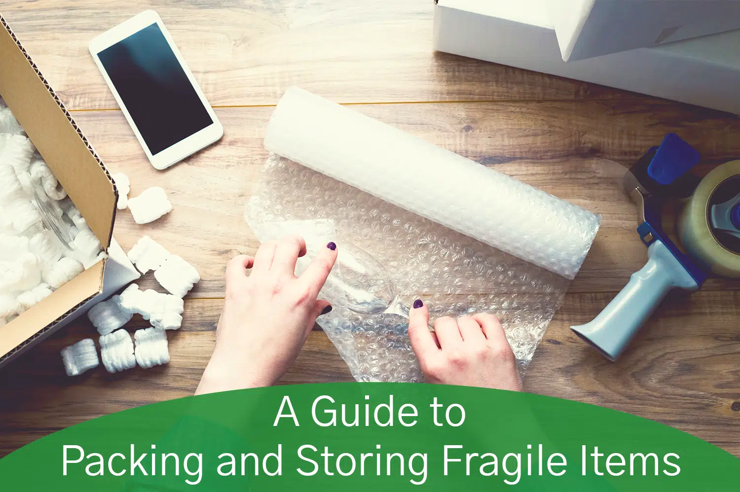 An anonymous person wrapping a fragile item (champagne flute) in bubble wrap on a wooden table surrounded in packing peanuts.