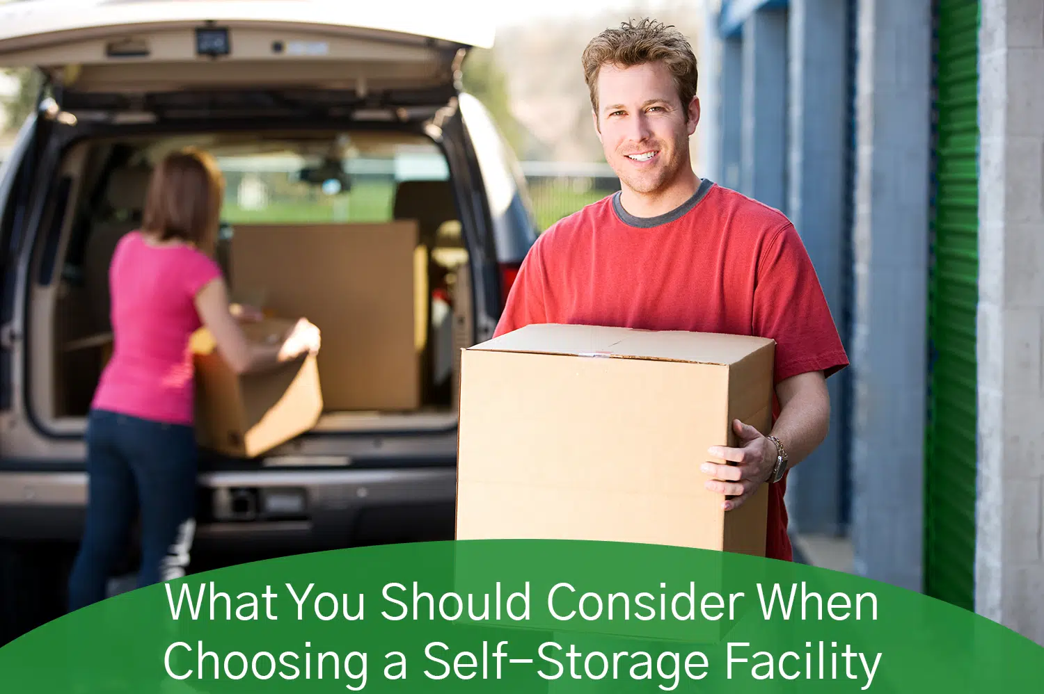 White man in red t-shirt holding a cardboard box, ready to put it in his self-storage facility unit.