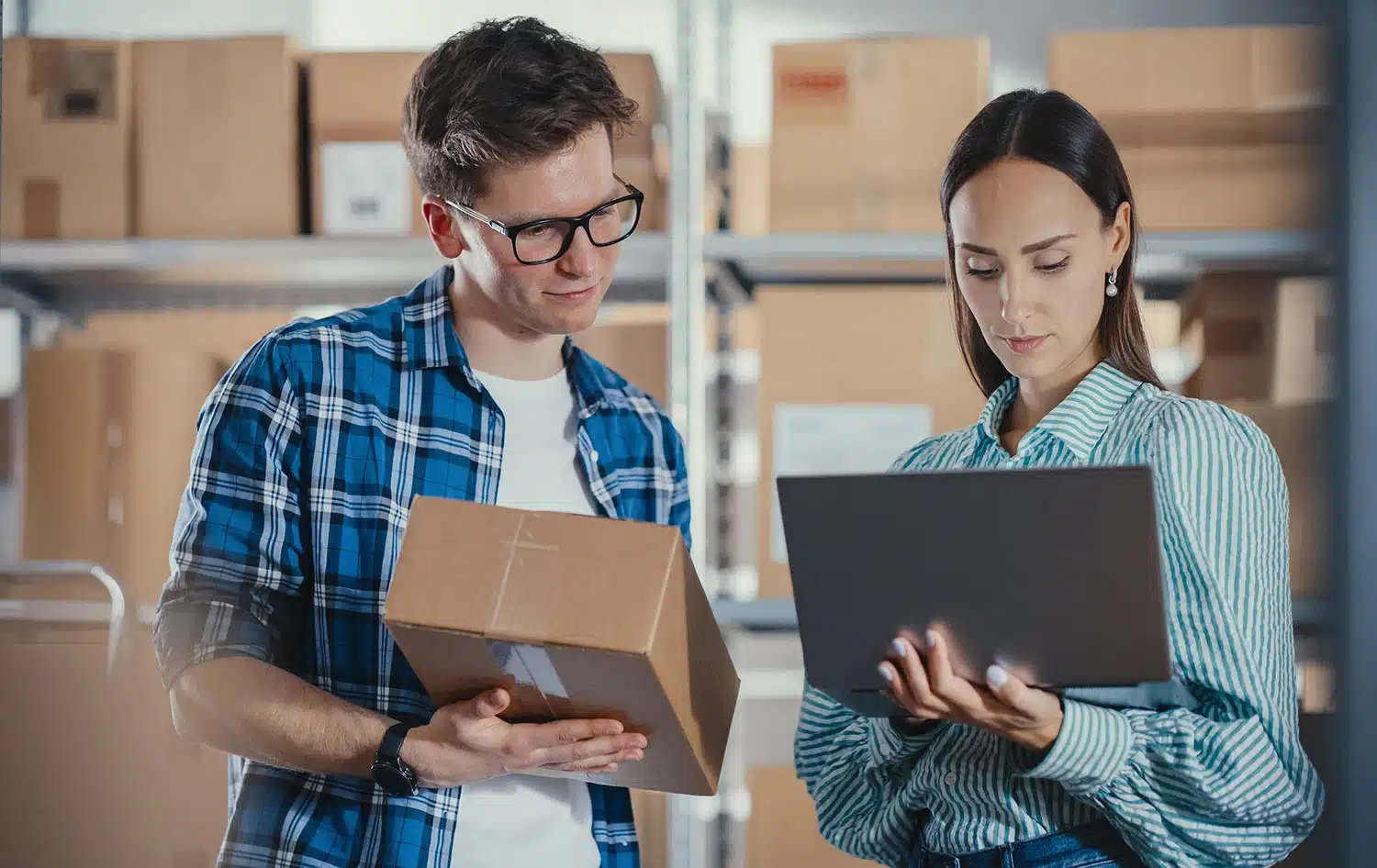 Small business owners on looking at inventory with laptop in storage unit